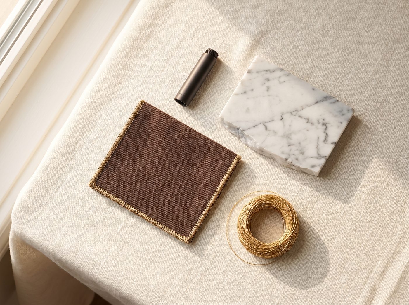 Elixir's materials palette — brown ballistic weave, Carrara marble, anodised metal and gold thread
